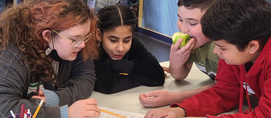 Four students looking at document on table