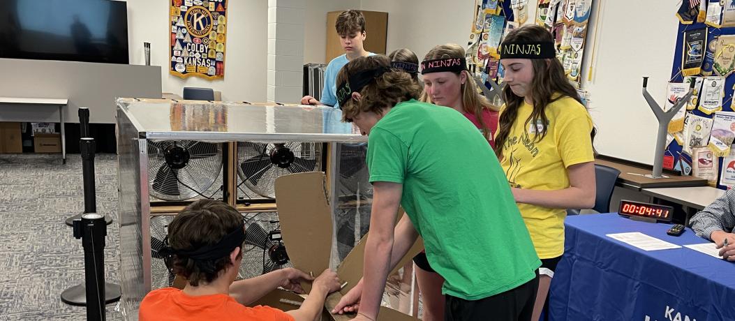 Students working on wind turbine while wearing headbands that say "Neon Ninjas"