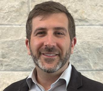 Man wearing dress shirt and jacket in front of limestone wall (2025)