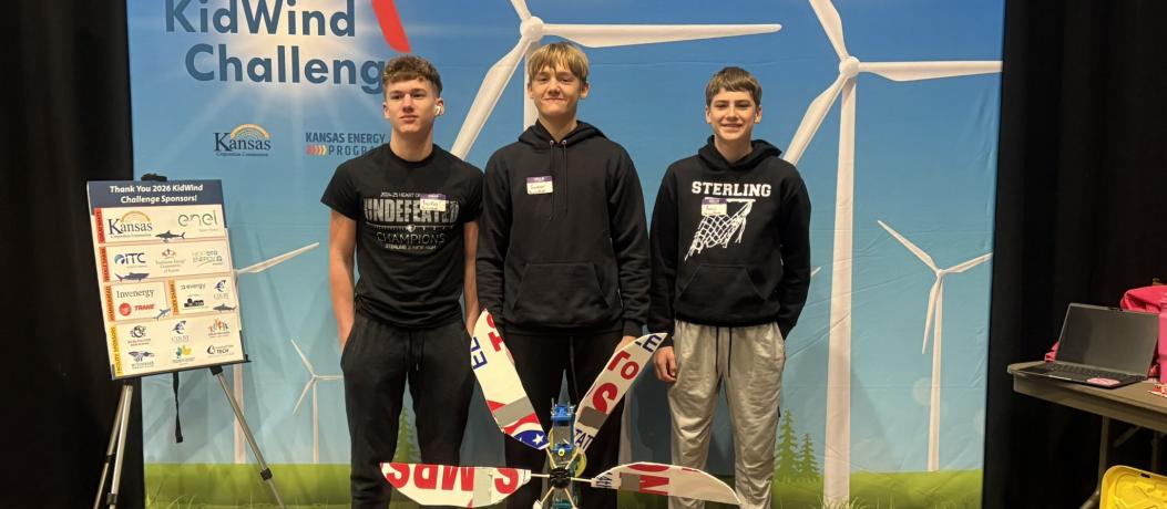 Students standing with turbine in front of sign